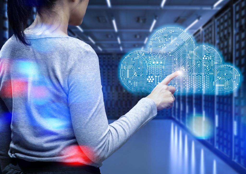 Woman in data center pointing at digital cloud visualization, representing cloud-based monitoring and management of infrastructure with circuit board pattern inside cloud symbol