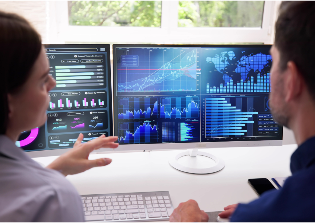 Business intelligence professionals analyzing big data governance dashboards on dual monitors, focusing on data governance strategies, frameworks, and tools for compliance and decision-making.