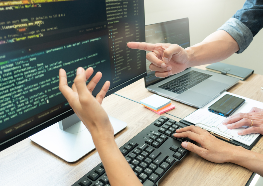 BizTalk Server Code Optimization: Two developers collaborating on code analysis for performance tuning, with visible code snippets and keyboard.